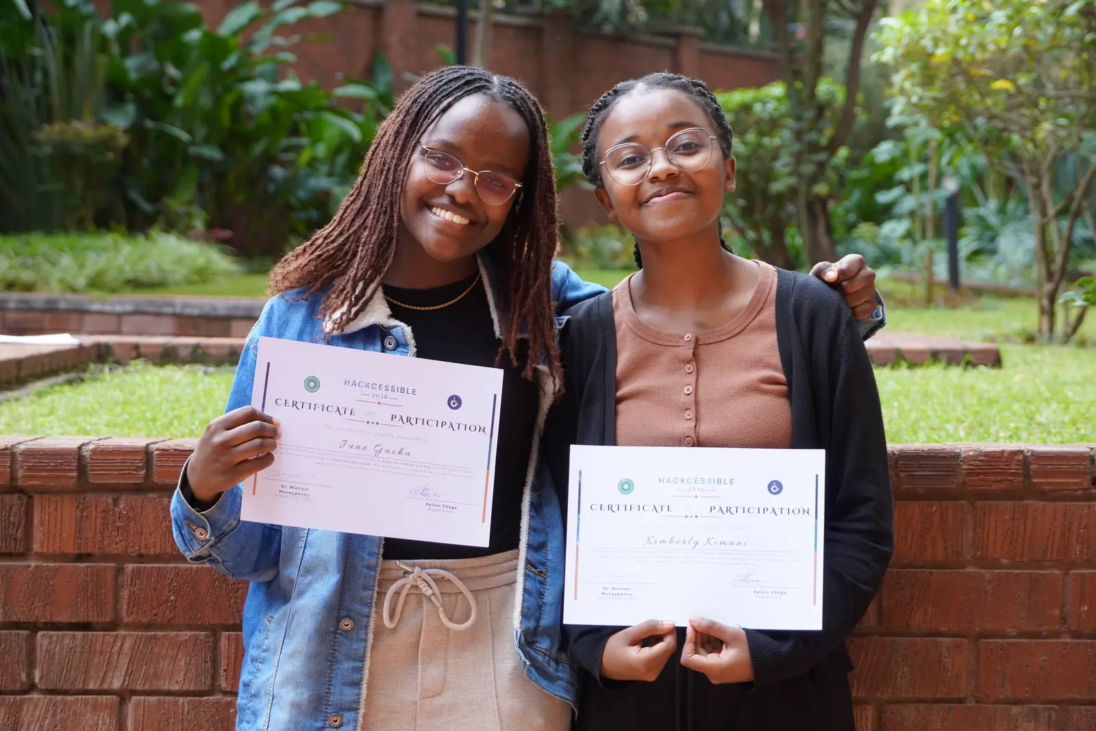 Two Hackcessible participants holding their certificates at Aga Khan University